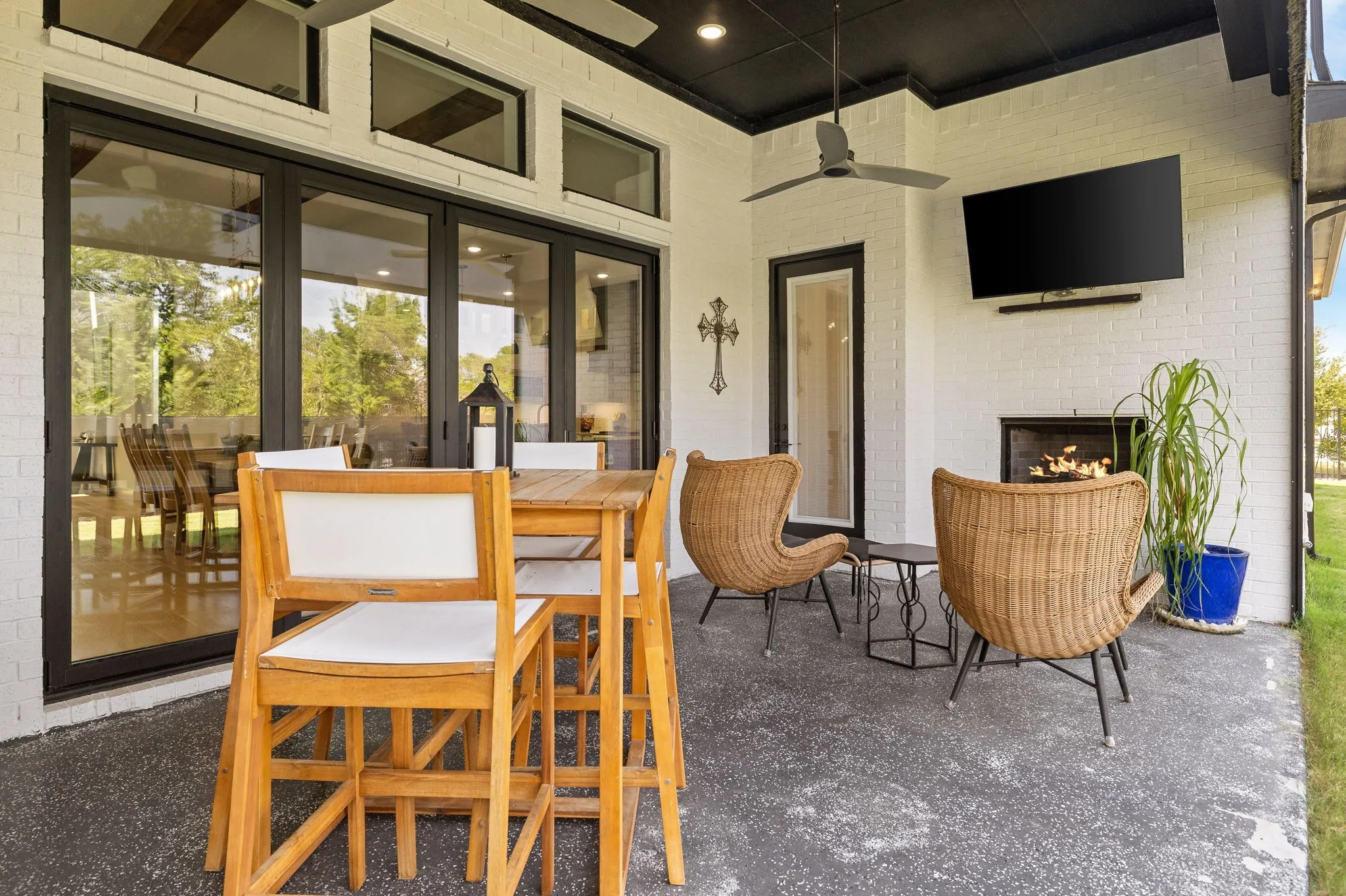 Covered patio featuring a ceiling fan, a mounted television, a fireplace, and a large sliding glass door