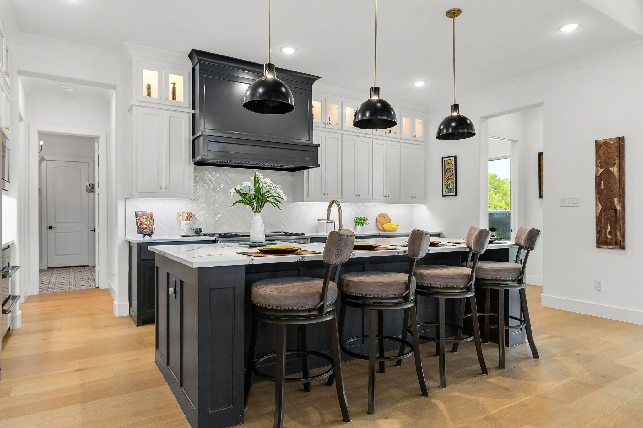 Kitchen featuring a central island with countertop seating, white upper cabinetry, dark lower cabinetry, and wood-finish flooring