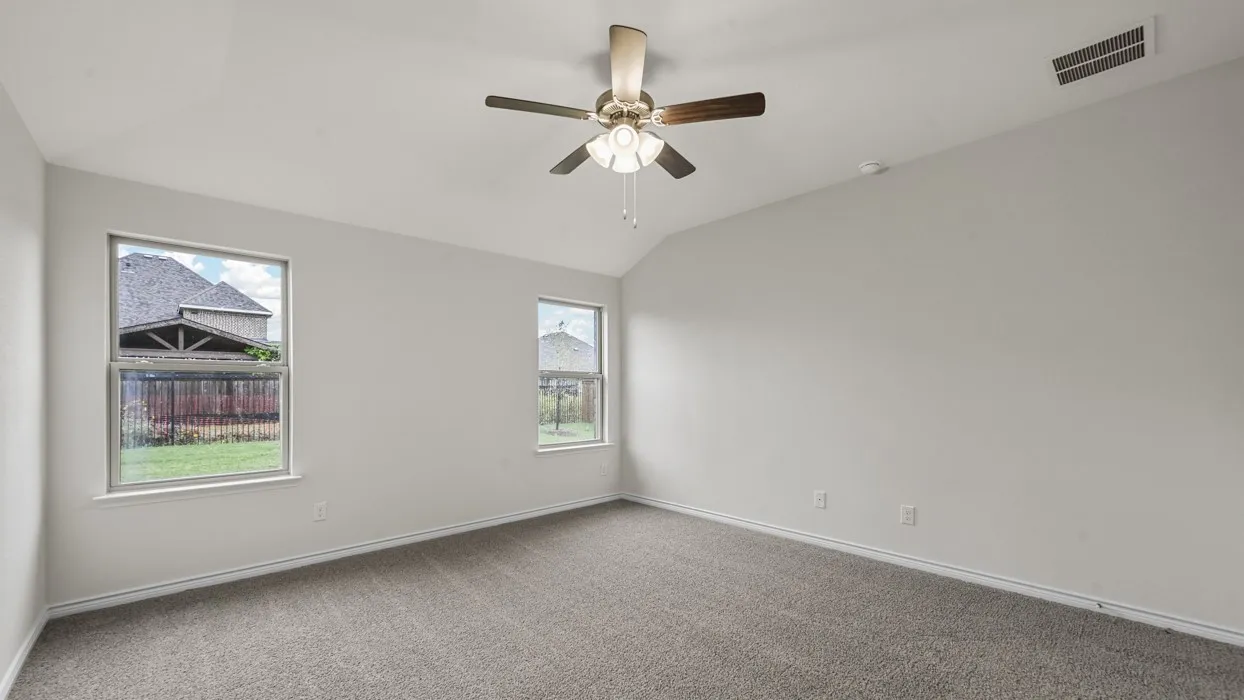 Spacious room featuring vaulted ceilings, neutral-toned carpeting, two windows, and a ceiling fan with integrated lighting