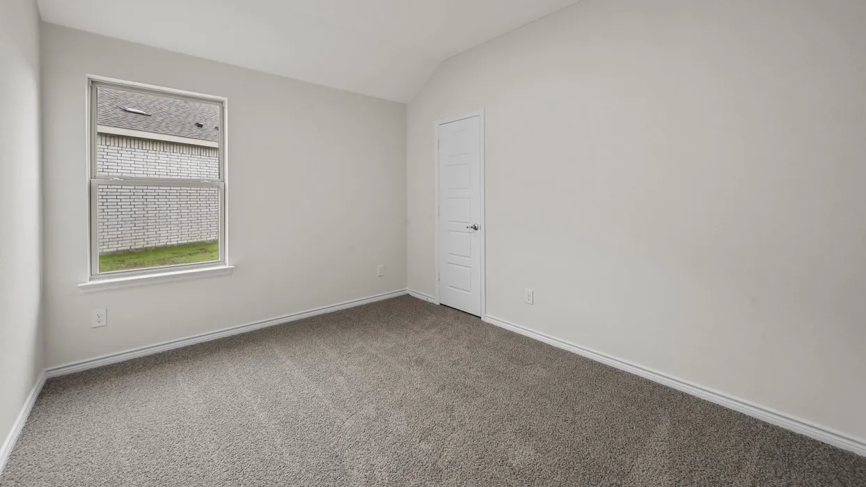 Bright secondary bedroom featuring neutral wall finishes, neutral carpet flooring, and a window with cellular shade providing natural light