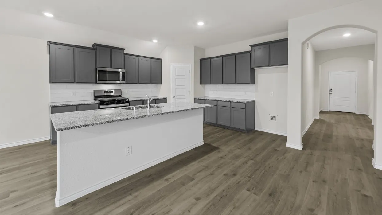 Kitchen with dark gray cabinetry, stainless steel appliances, a white subway tile backsplash, and light-toned countertops