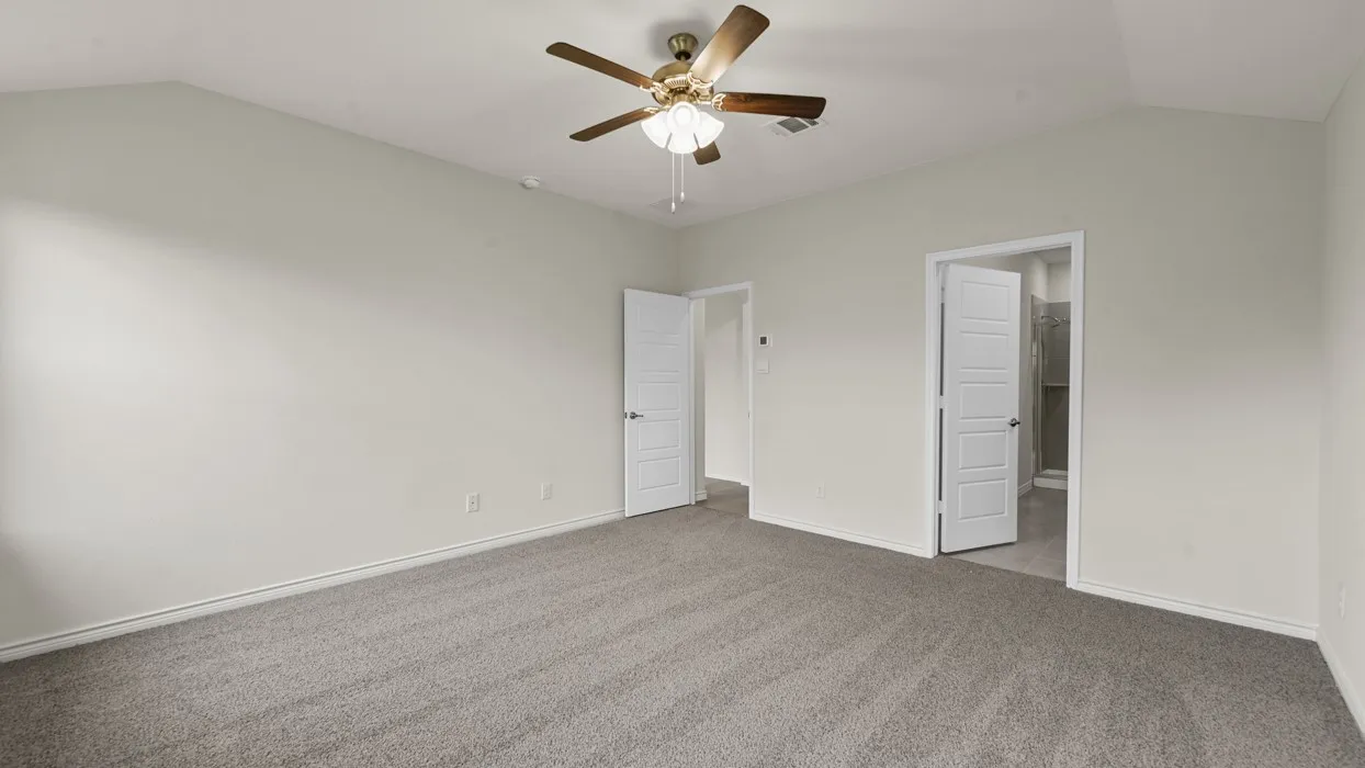 Spacious bedroom featuring neutral wall finishes, plush carpeting, ceiling fan with integrated lighting, and dual closet access with louvered doors