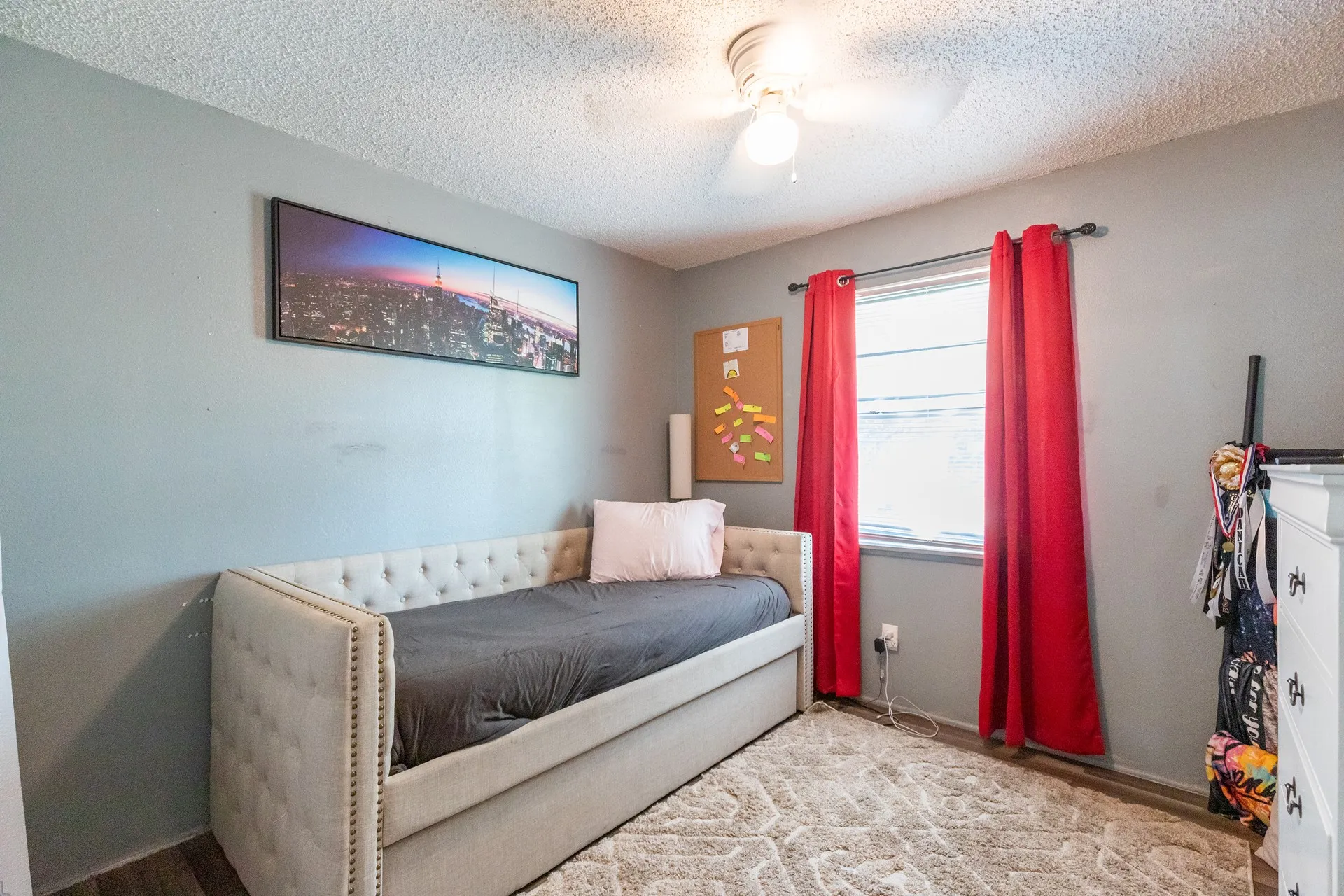 Wood-finish flooring, ceiling fan with integrated lighting, and a single window providing natural illumination
