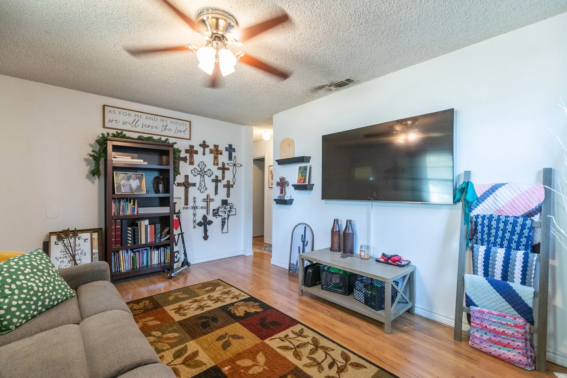 Wood-finish flooring with white walls and a ceiling fan with light fixture