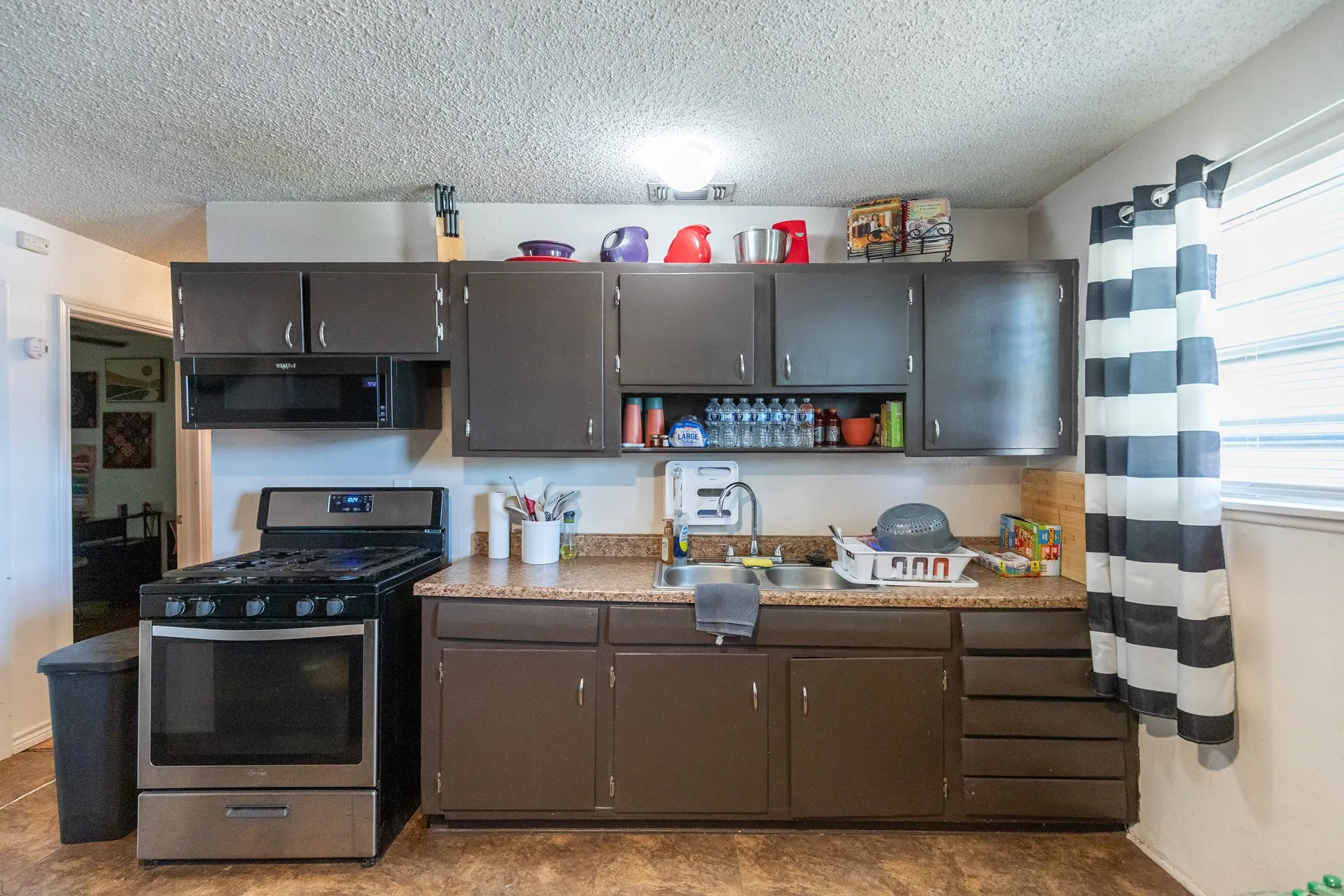 Kitchen featuring dark wood-finish cabinetry, stainless steel range with microwave, and a double basin sink