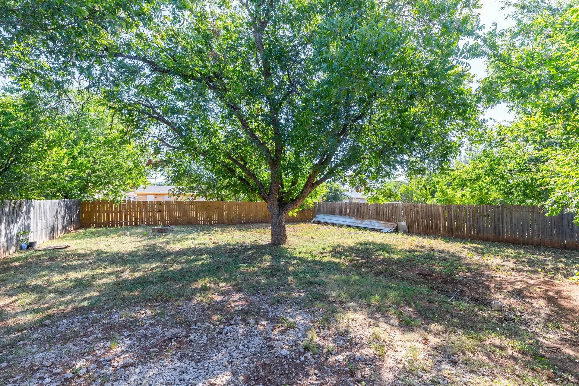Expansive backyard featuring mature trees and wood fencing