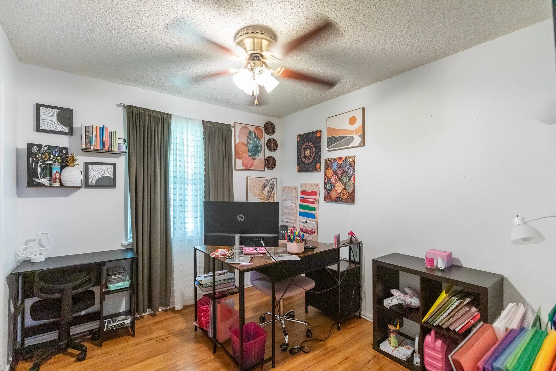 Wood-finish flooring with white walls and a ceiling fan