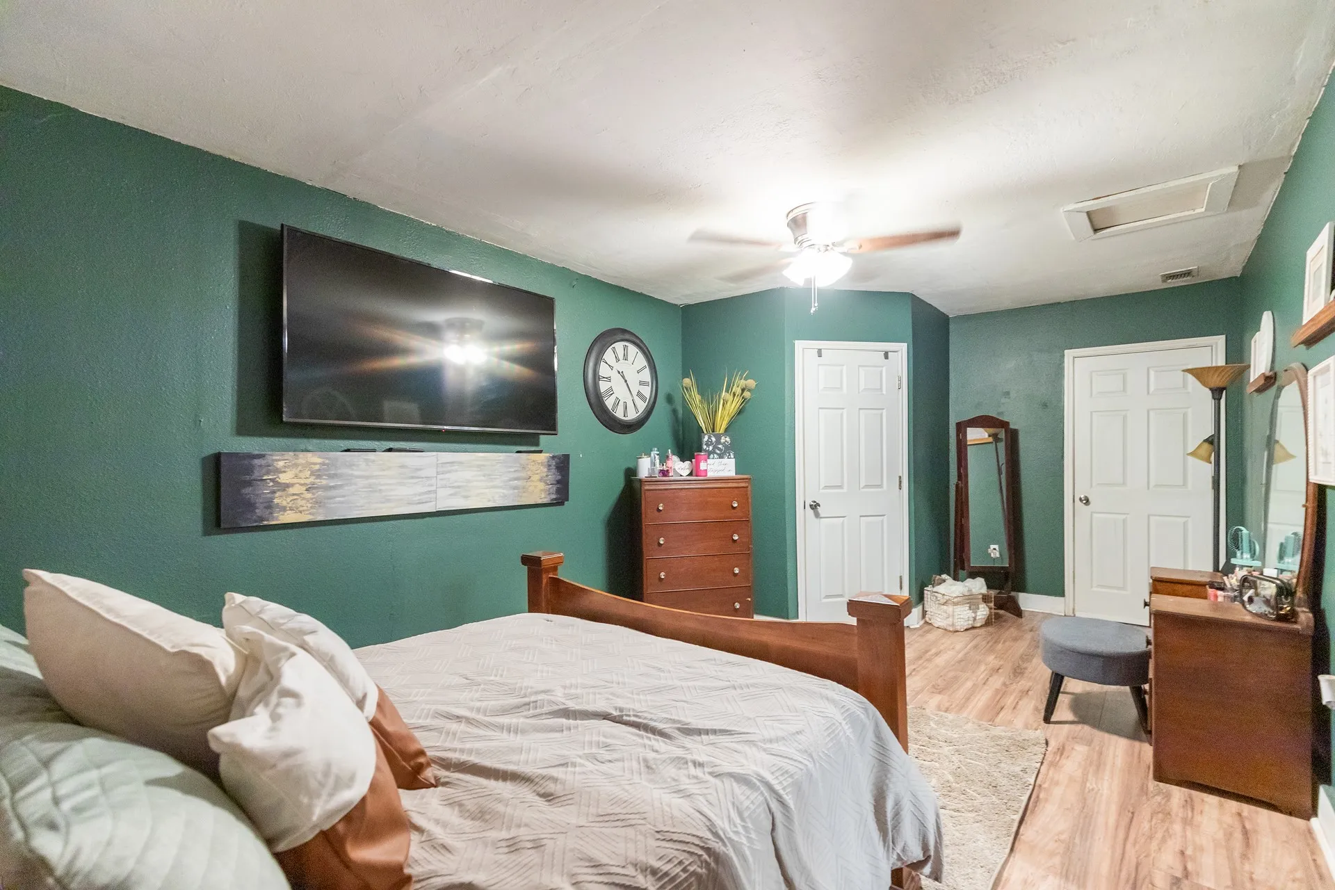 Wood-finish flooring with a ceiling fan light fixture and multiple paneled doors