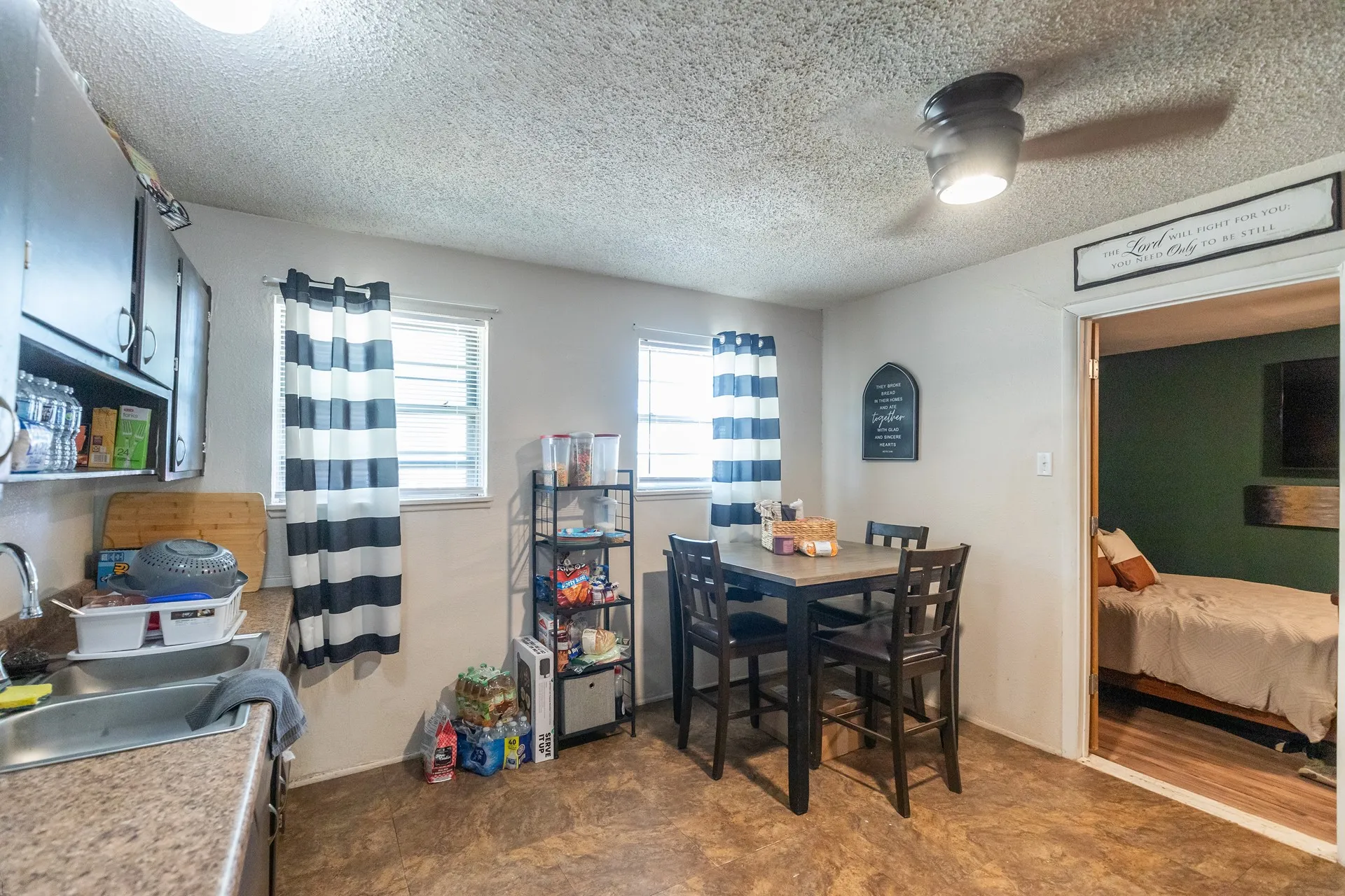 Functional kitchen space featuring a ceiling fan with integrated lighting, wood-finish flooring, and two windows providing natural light