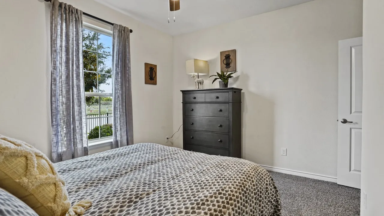 Carpeted flooring, white interior walls, white window frame, white interior door, and a ceiling fan with integrated lighting