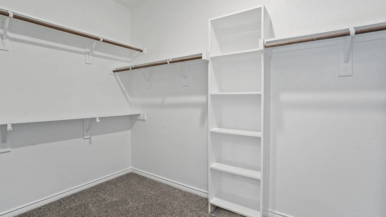 Built-in white shelving, wood-finish hanging rods, and grey carpet flooring