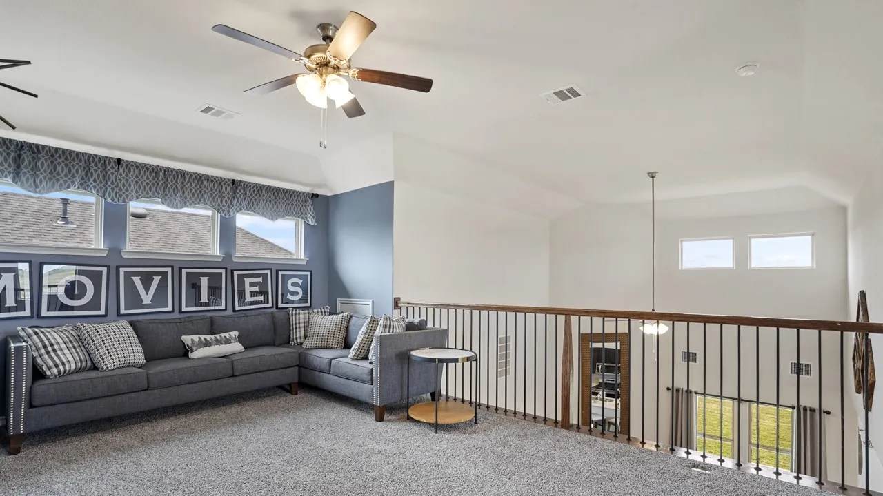 Carpeted loft area featuring a ceiling fan, multiple windows, and an open railing overlooking the space below