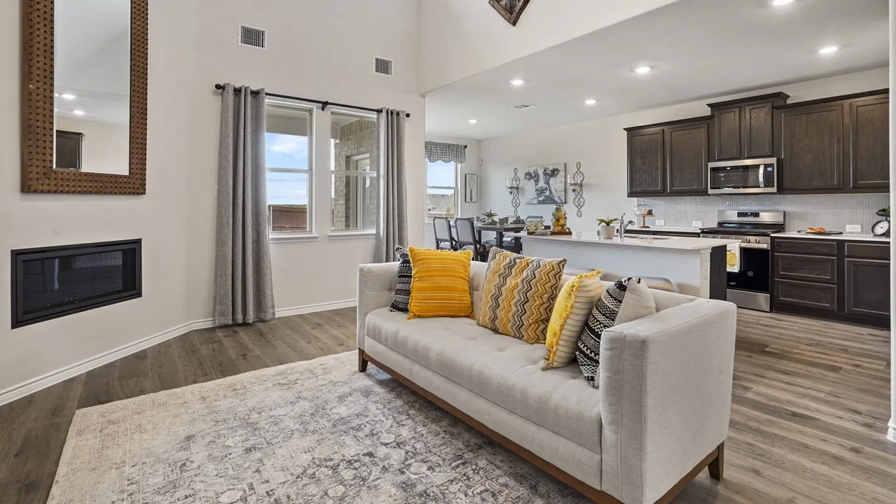 Vaulted ceiling with recessed lighting, linear electric fireplace, wood-finish flooring, kitchen island with countertop seating, and stainless steel appliances
