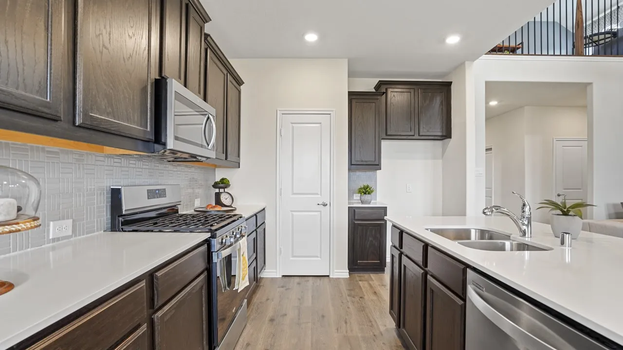 Kitchen featuring dark wood-finish cabinetry, stainless steel appliances, light countertops, a tile backsplash, and wood-finish flooring