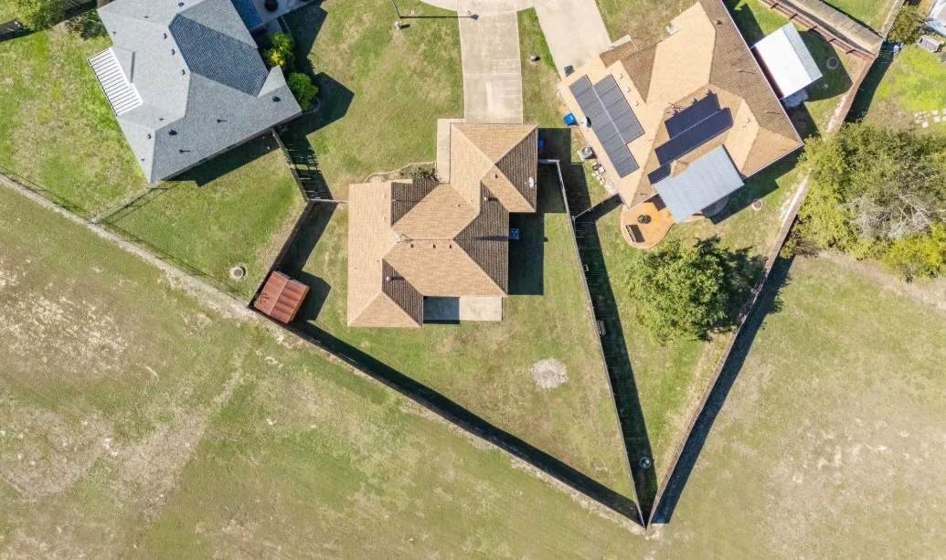 Property featuring a brown shingle roof, a concrete driveway, and solar panels