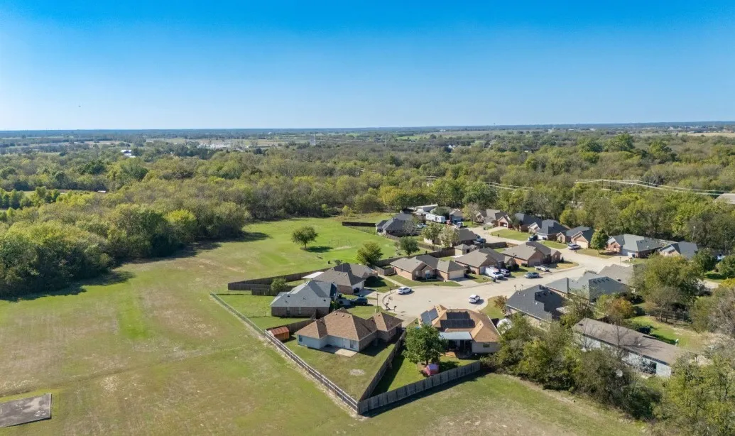 Residential properties with mature trees, fenced backyards, and expansive green spaces