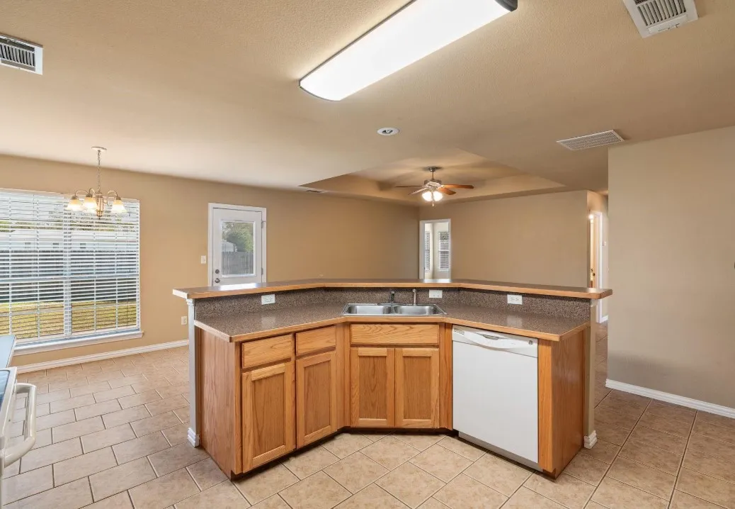 Kitchen featuring a dual-basin sink, wood cabinetry, and a dishwasher