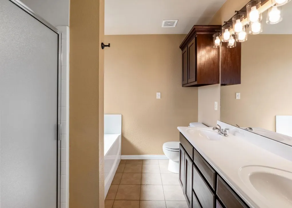 Dual vanity with integrated sinks, dark wood-finish cabinetry, and a large mirror