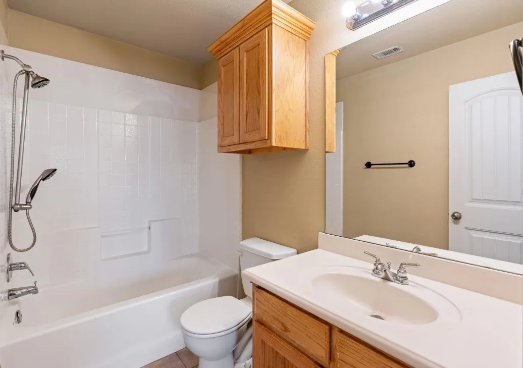 White tile surround bathtub with a shower head and handheld sprayer
