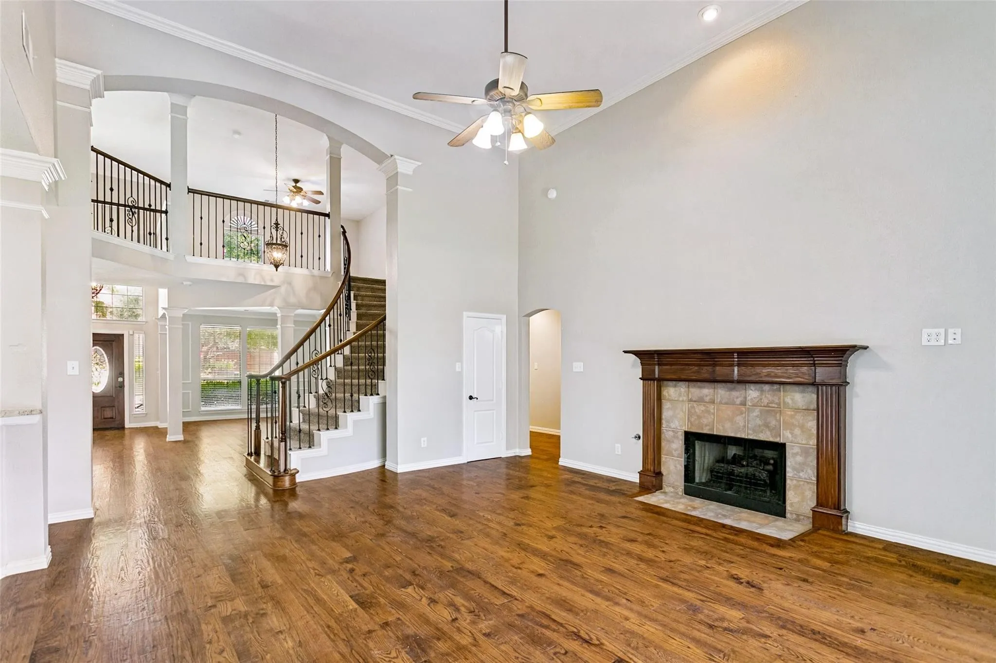 Expansive living area featuring soaring ceilings, wood-finish flooring, and a fireplace with a wood mantle and tile surround