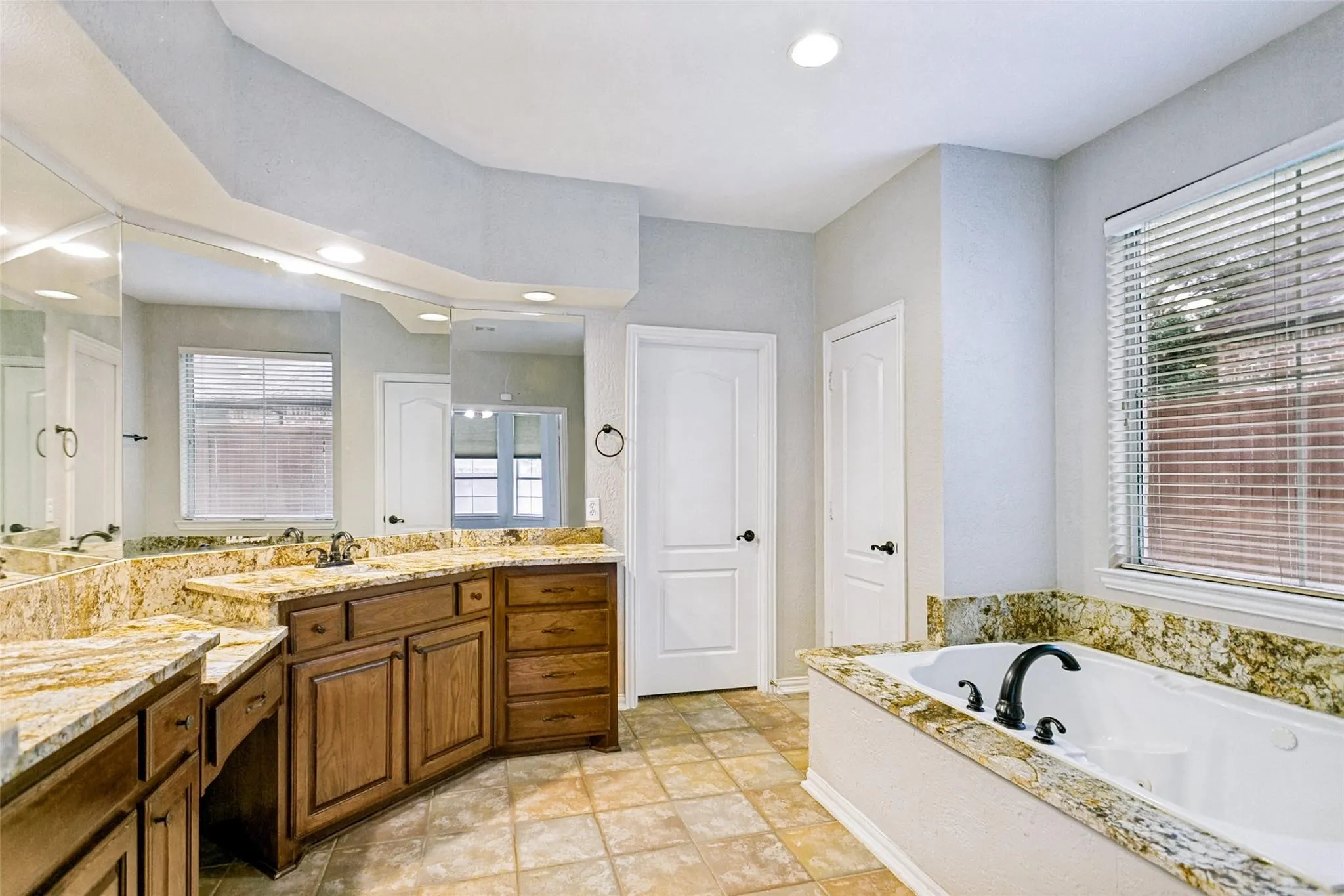 Dual vanity with granite countertops, recessed lighting, built-in soaking tub, and tile flooring