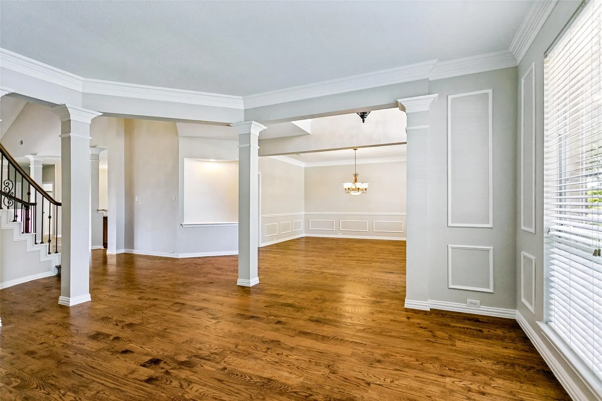 Grand foyer featuring a curved staircase with wrought iron balusters and wood handrails, wood-finish flooring, decorative entryway lighting, and extensive trim work