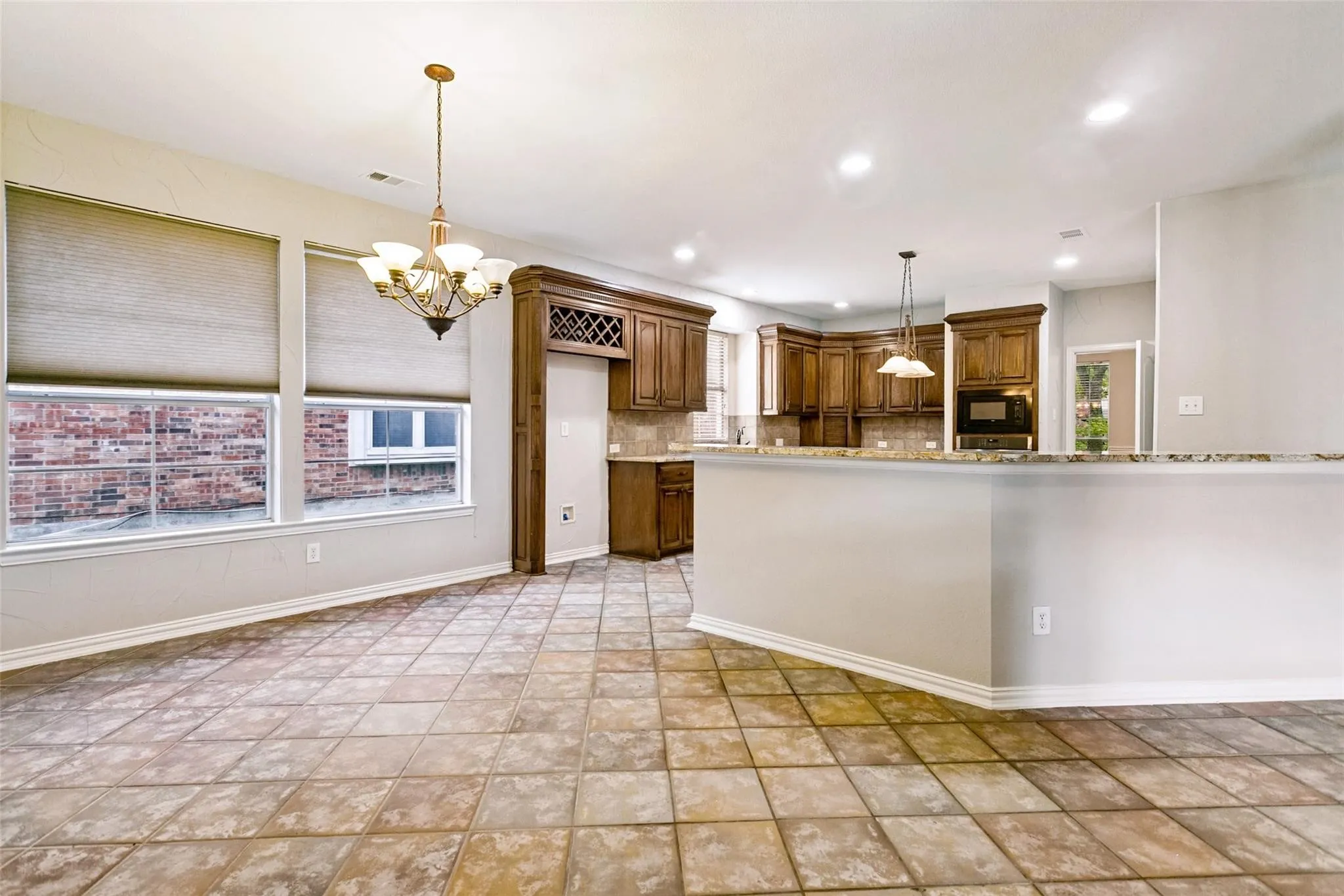 Spacious open-concept kitchen and dining area featuring wood-finish cabinetry, stainless steel appliances, granite countertops, and a large center island with seating