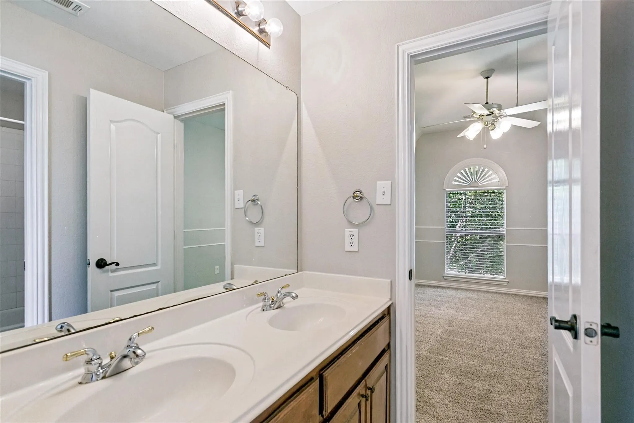 Dual vanity with integrated sinks, wood-finish cabinetry, and a full-width mirror