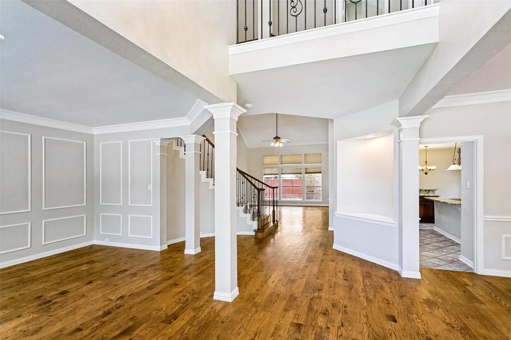 Grand foyer featuring a curved staircase with wrought iron balusters and wood handrails, wood-finish flooring, decorative entryway lighting, and extensive trim work