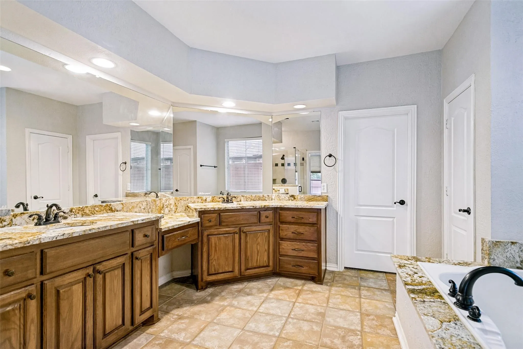 Dual wood-finish vanities with undermount sinks and extensive countertop space