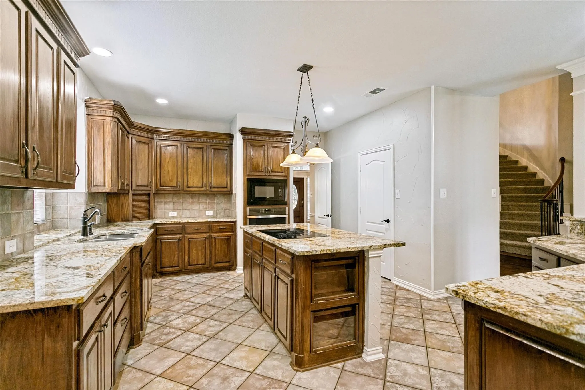 Kitchen featuring wood cabinetry, stone countertops, a central island, integrated appliances, and diagonal tile flooring