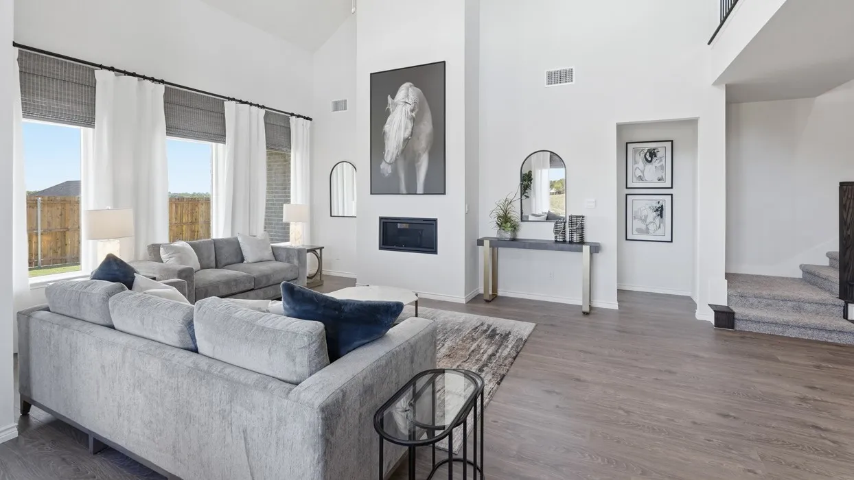 Vaulted ceiling, recessed fireplace, wood-finish flooring, large windows, and a staircase with carpeted treads
