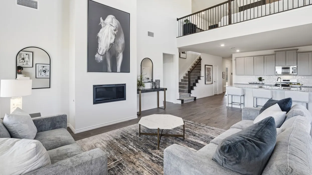 Open-concept living space with a tall ceiling, a built-in fireplace, wood-finish flooring, and a kitchen island with seating
