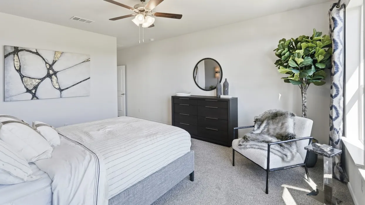 Plush carpeting, ceiling fan with integrated lighting, and a window for natural illumination