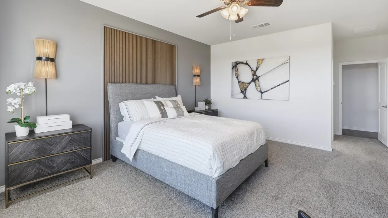 Wood-slatted accent wall, ceiling fan, neutral wall colors, light gray carpeting, and a doorway