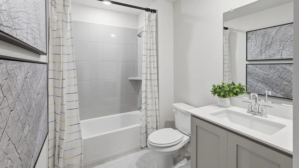 Bathroom featuring a gray vanity with an integrated sink, polished chrome faucet, a wall-mounted mirror, and a white toilet