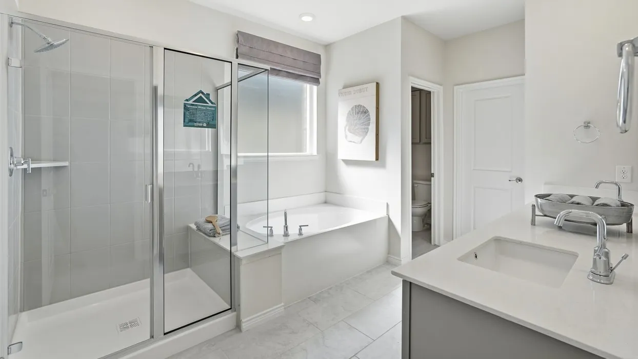 Glass-enclosed shower, built-in bathtub, single vanity with integrated sink, quartz countertop, and large window with roller​​‌​​​​‌​​‌‌​‌‌​​​‌‌​‌​‌​‌​​​‌​​ shade