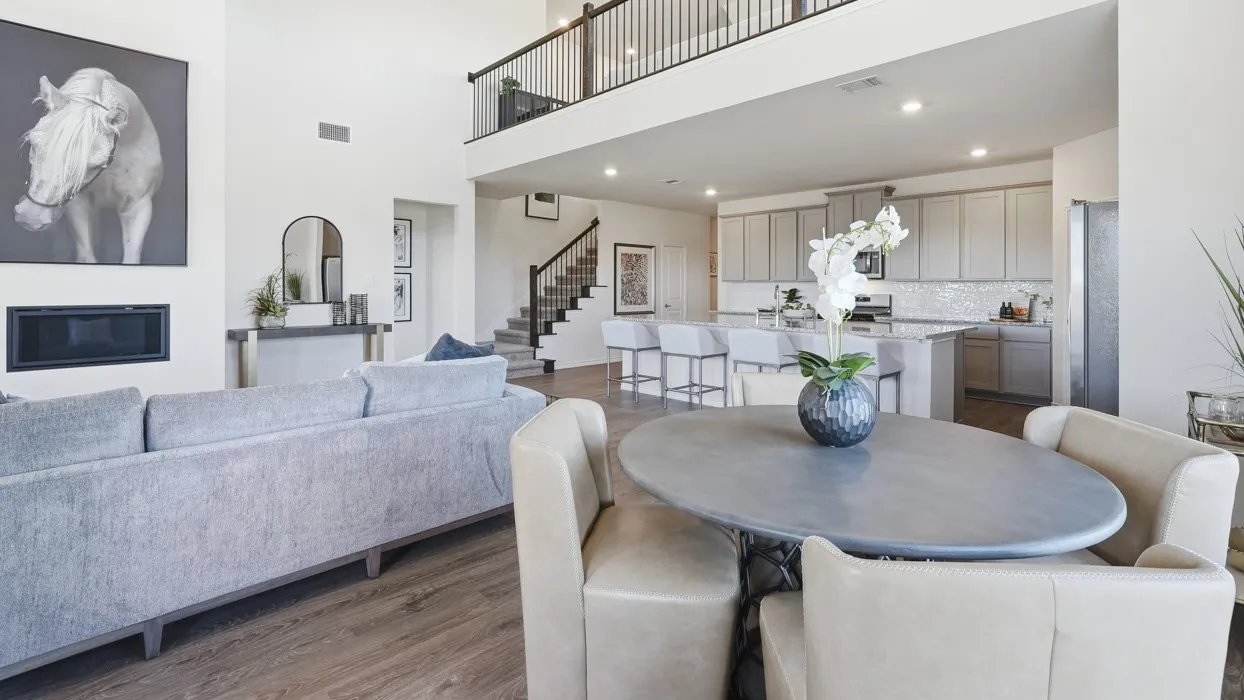 Two-story living area with wood-finish flooring, a linear fireplace, and a second-story interior balcony