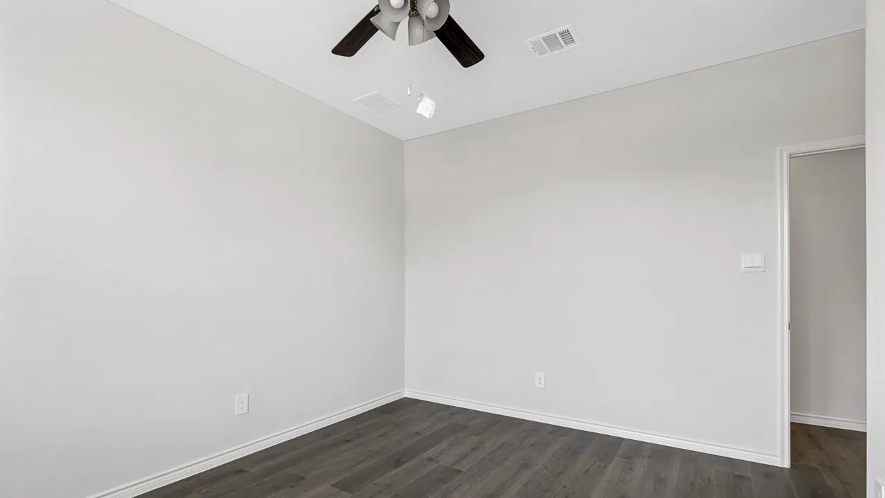 Wood-finish flooring, white walls, and a ceiling fan with integrated lighting