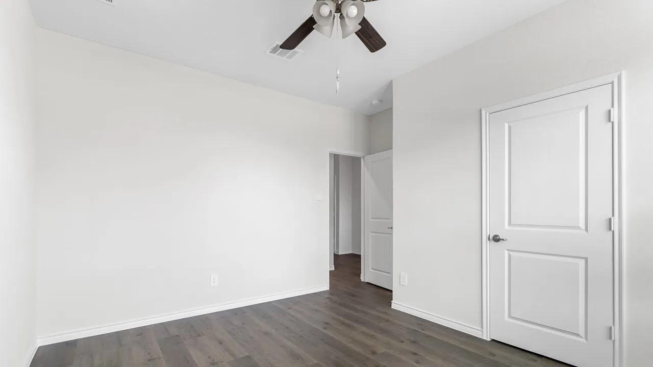Wood-finish flooring, white paneled doors, and a ceiling fan with light fixture