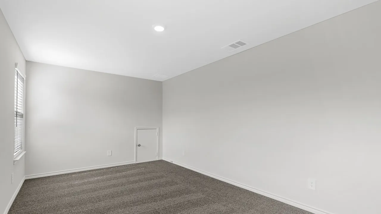 Recessed ceiling light, neutral wall paint, gray carpet flooring, white trim, and a white interior door