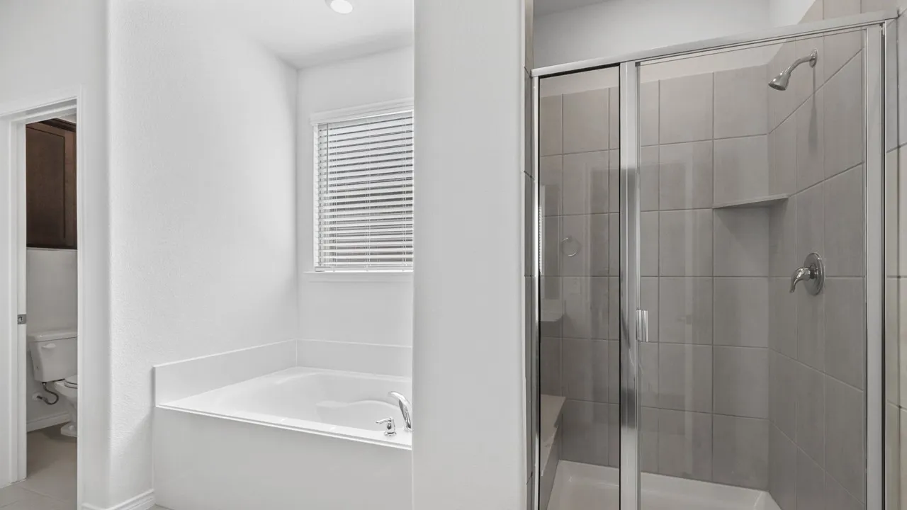 Soaking tub with a window, complete with a glass-enclosed shower featuring tiled walls and a built-in shower niche