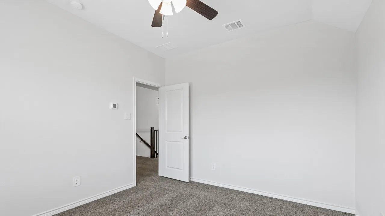 Carpeted flooring, vaulted ceiling, ceiling fan, white paneled door, and neutral wall tones