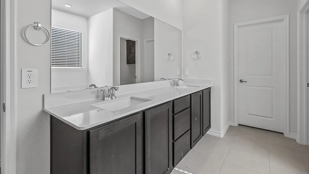 Dual vanity with integrated sinks, dark wood-finish cabinetry, and a large wall-mounted mirror