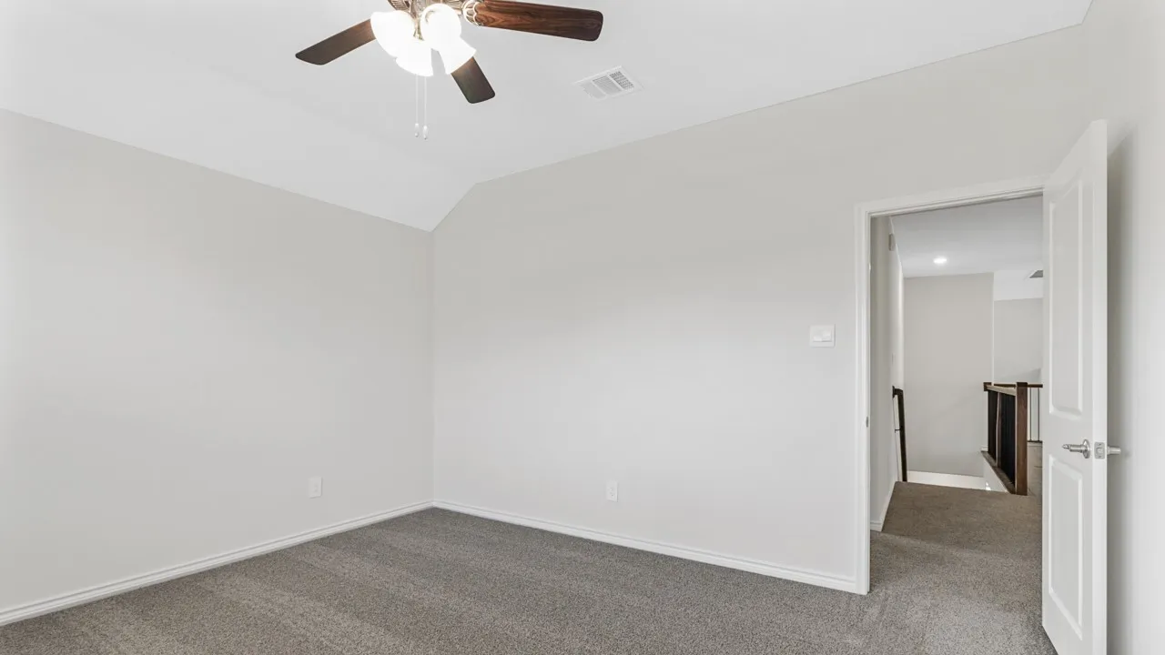 Vaulted ceiling with an attached ceiling fan, neutral wall paint, and gray carpeting