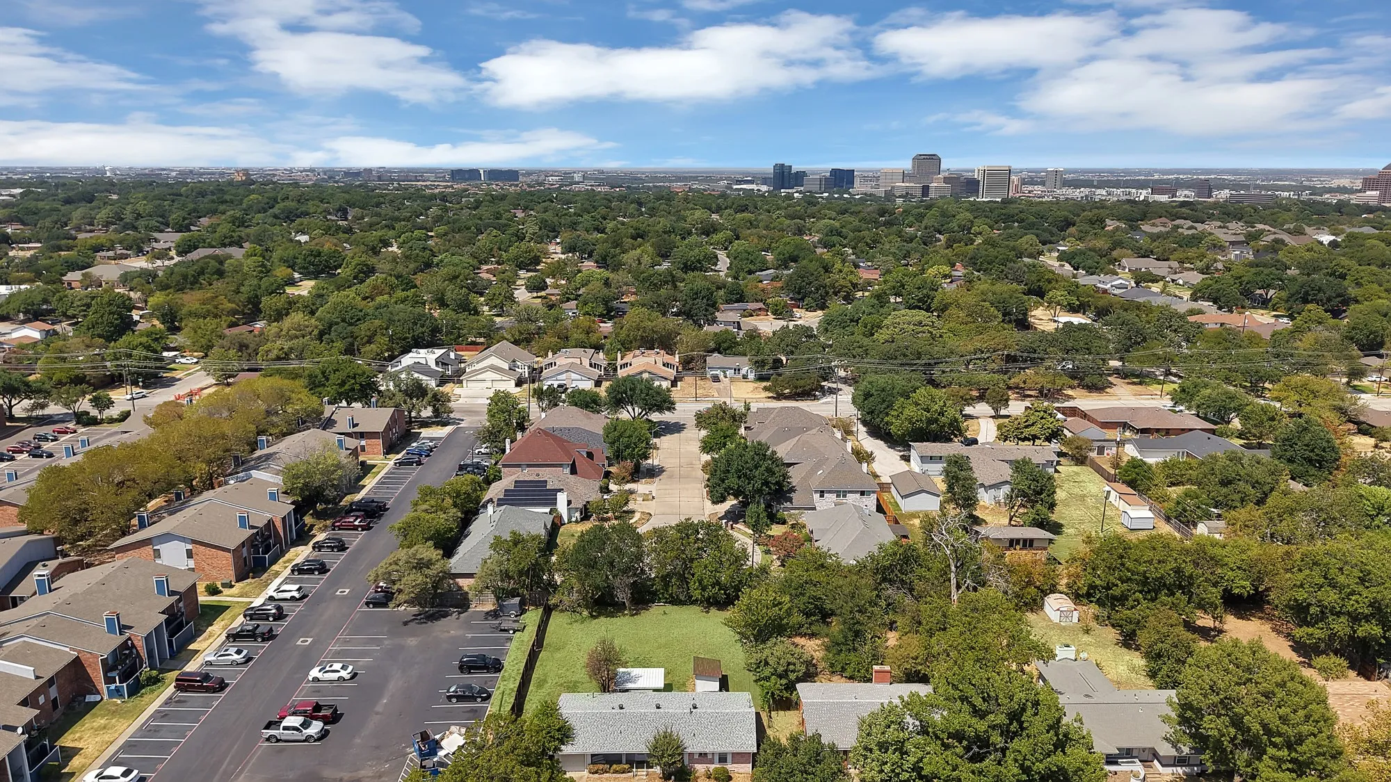 Expansive residential area with a dense tree canopy and distant urban skyline