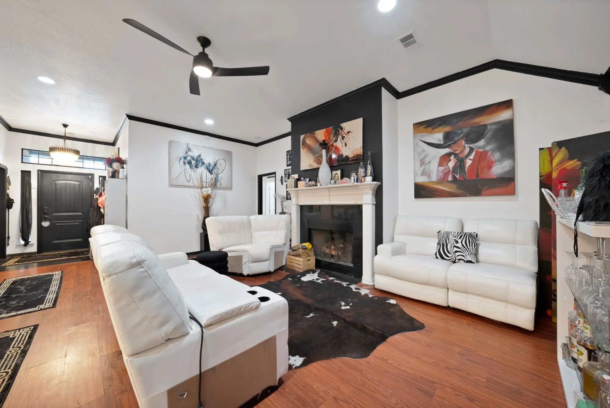 Warm wood-finish flooring with a white wood mantel fireplace and black surround
