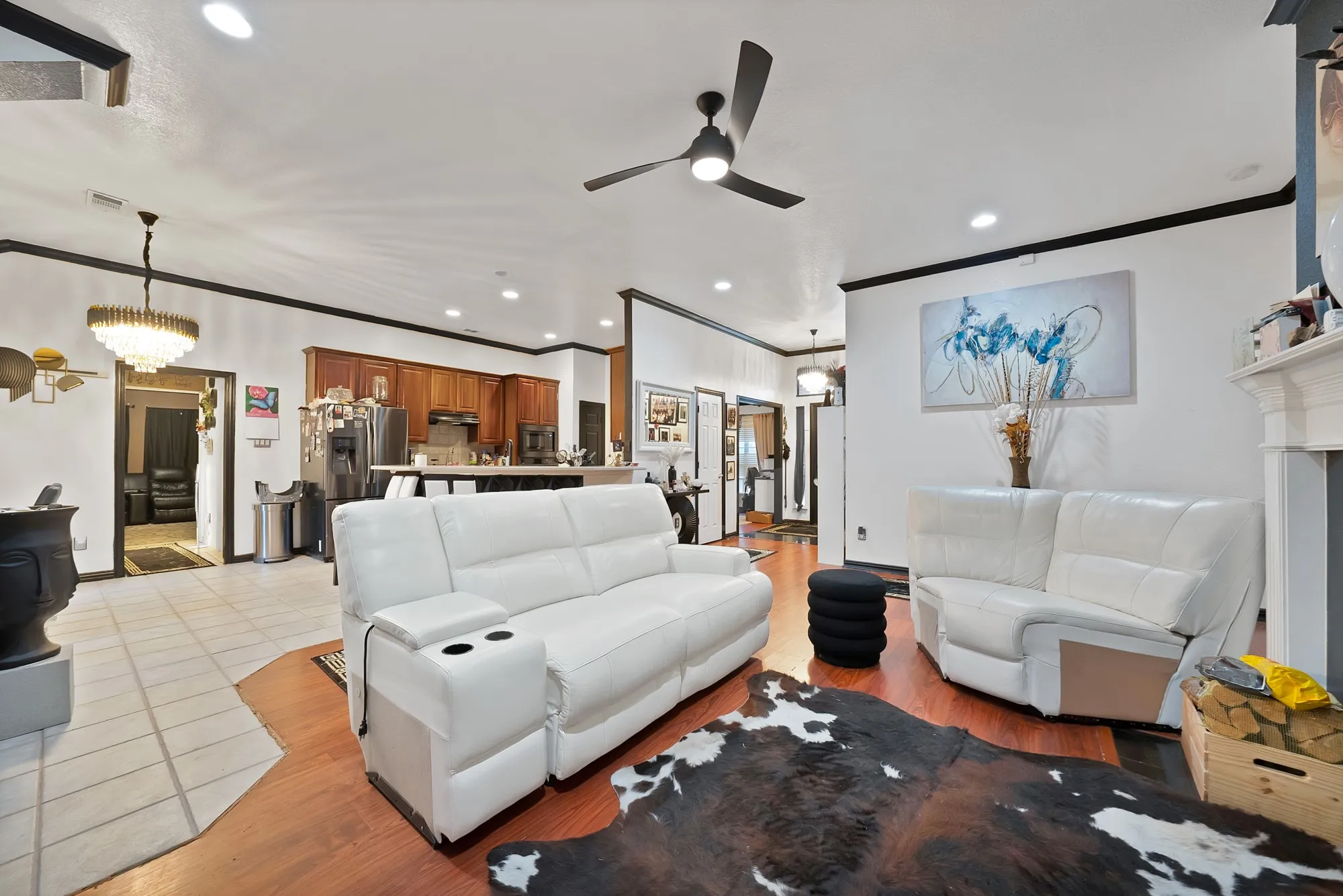 Hardwood-finish flooring, recessed lighting, ceiling fan, crown molding, and a fireplace with a mantel