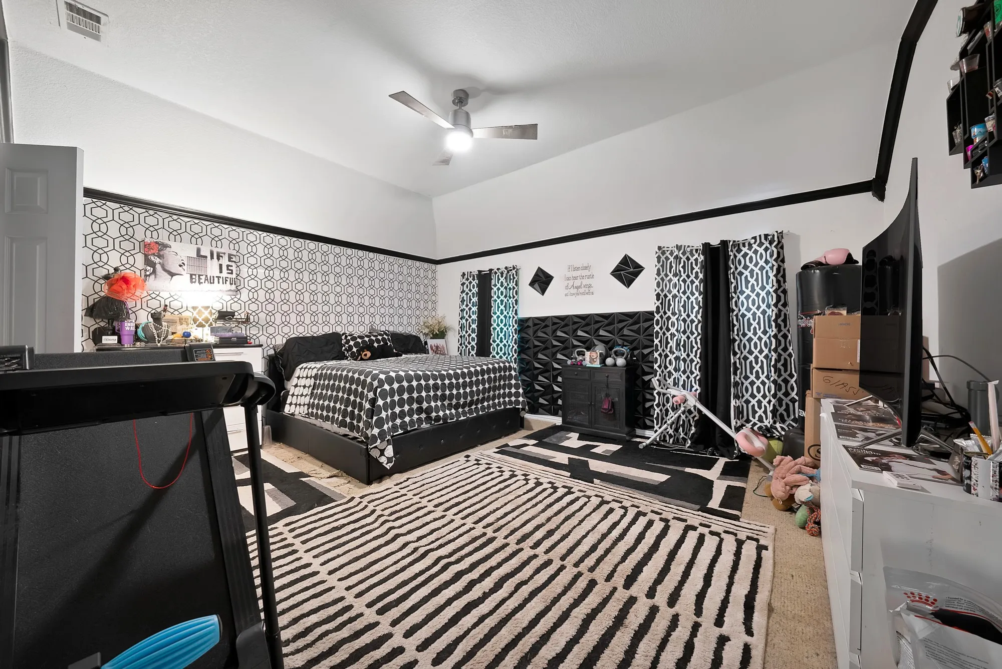 Vented ceiling fan, vaulted ceiling, white walls, black accent trim, patterned wallpaper accent wall