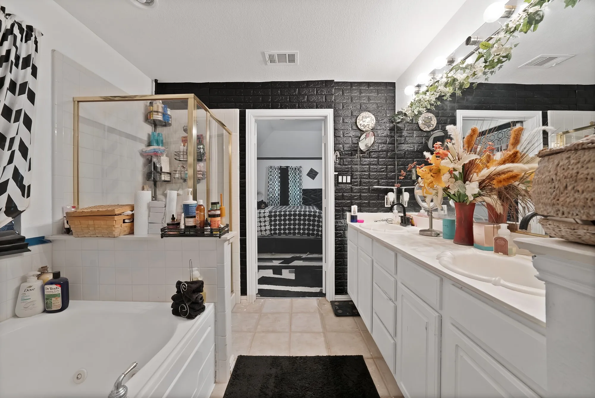 Dual vanity with white cabinetry, tile flooring, built-in bathtub, and a glass-enclosed shower